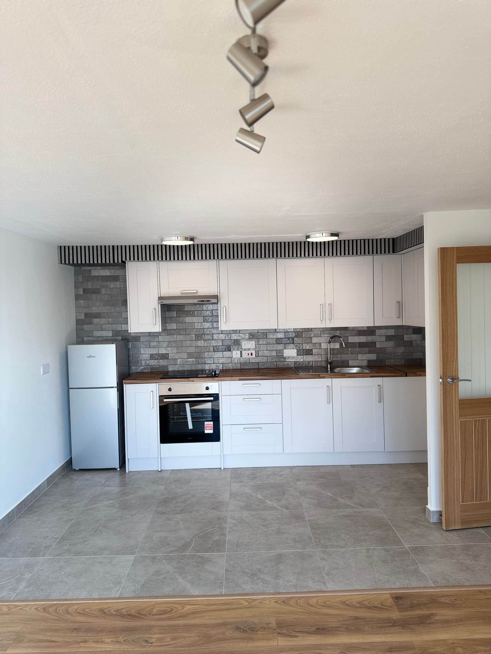 New grey kitchen with brick-effect splashback, wood worktop and integrated oven, Osprey House Hove